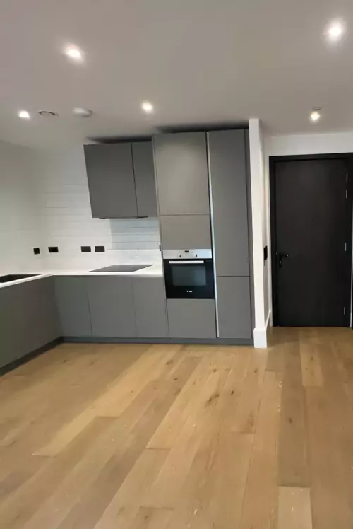 Side view of man installing cabinet shelf in a modern white kitchen.
